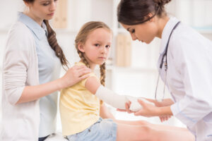 pediatrician doctor bandaging child's arm