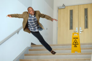 african American businessman falling on stairwell with yellow warning sign on steps
